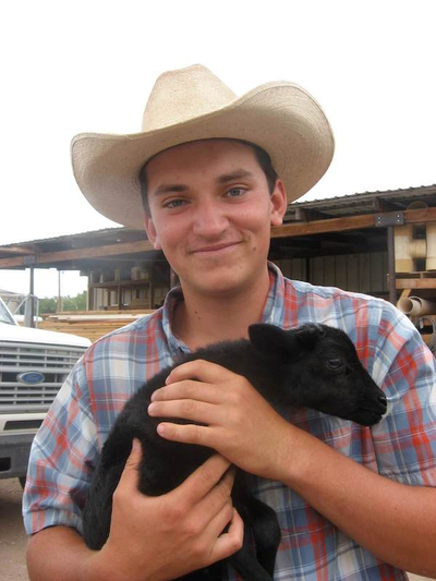Young man holding a baby calf.